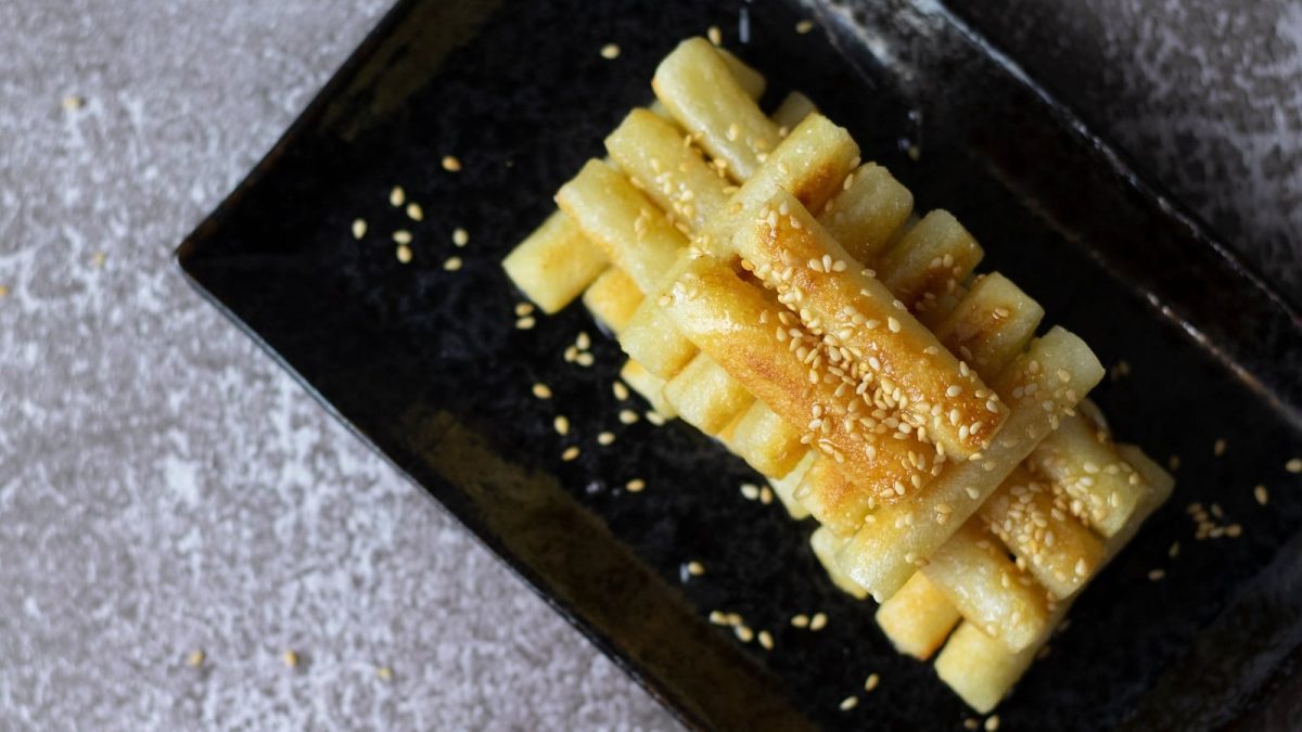 Eine Portion koreanischer Honig-Reiskuchen auf einem schwarzen Tablett.