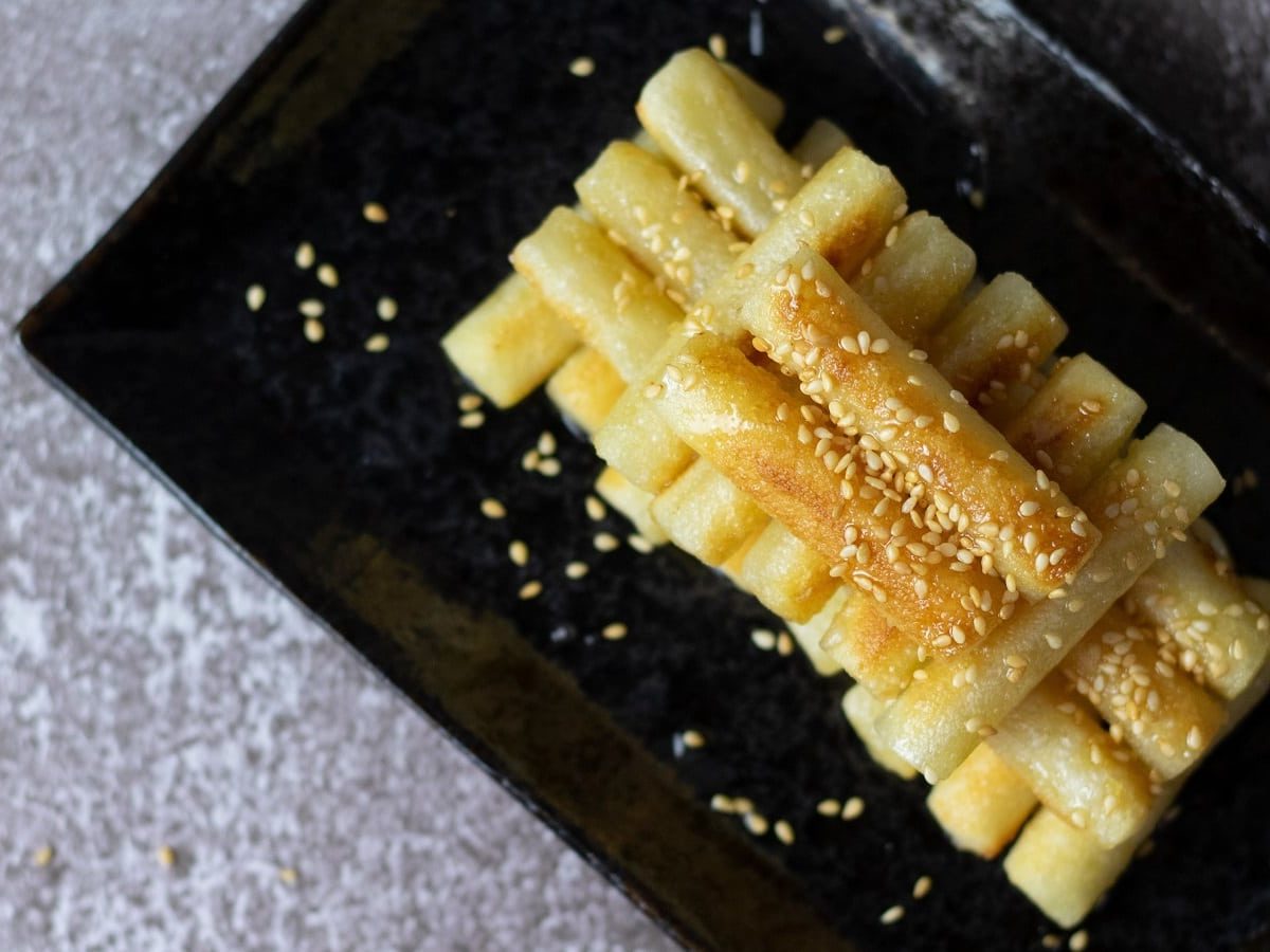 Eine Portion koreanischer Honig-Reiskuchen auf einem schwarzen Tablett.