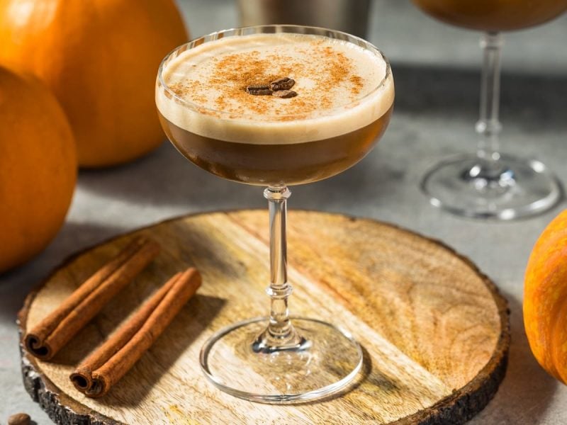 Ein Glas Pumpkin Spice Espresso Martini auf einer runden Baumscheibe.