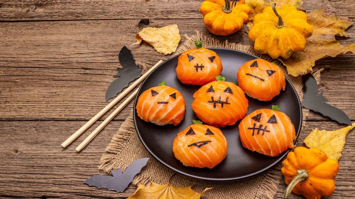 Ein schwarzer Teller mit dem Halloween Sushi auf einem rustikalem Holztisch von oben fotografiert.