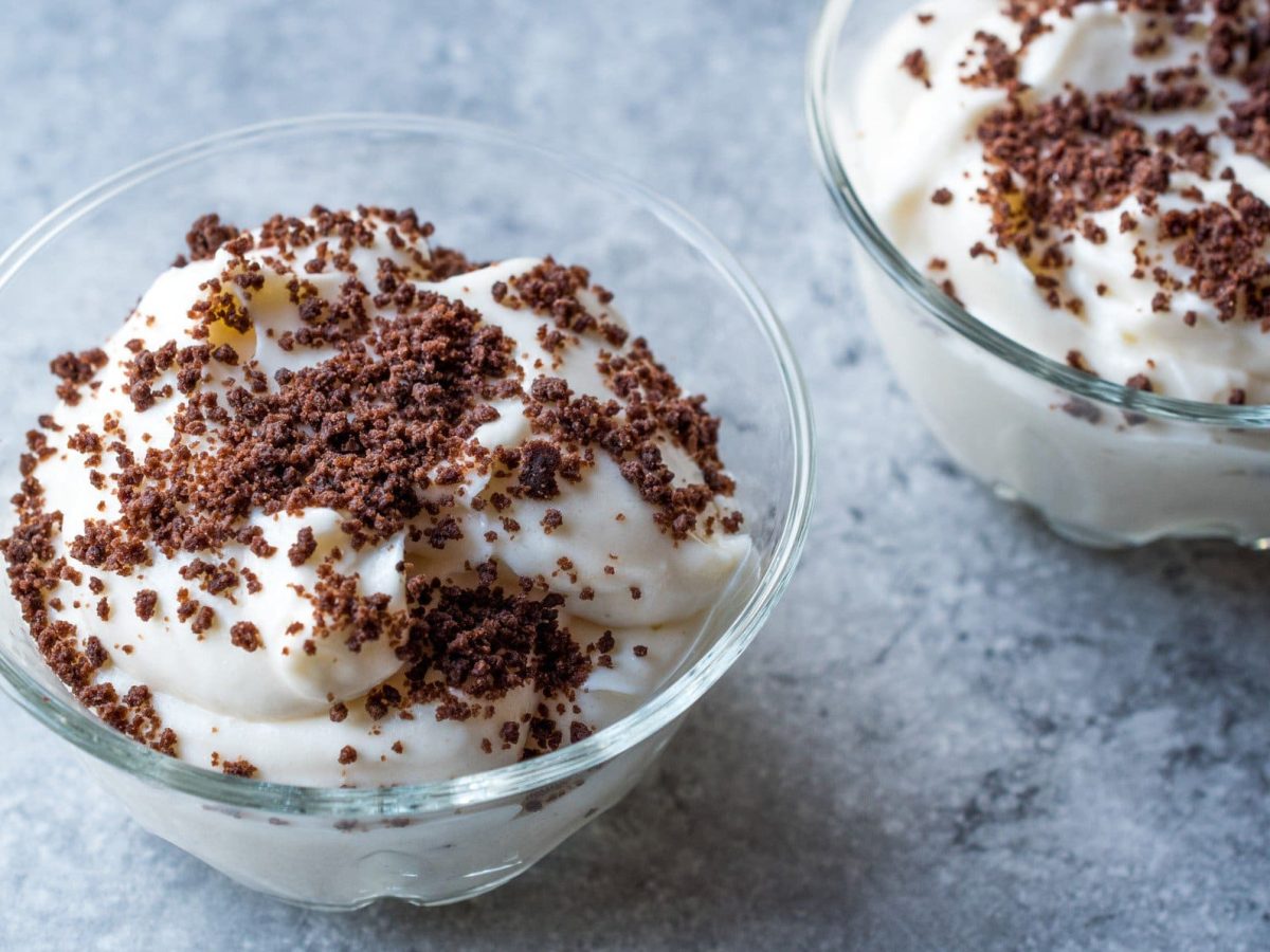 Maulwurfs-Dessert: Eine Schale gefüllt mit einer Quark-Joghurt-Mischung mit Banane und Kekskrümel auf marmoriertem Untergrund.