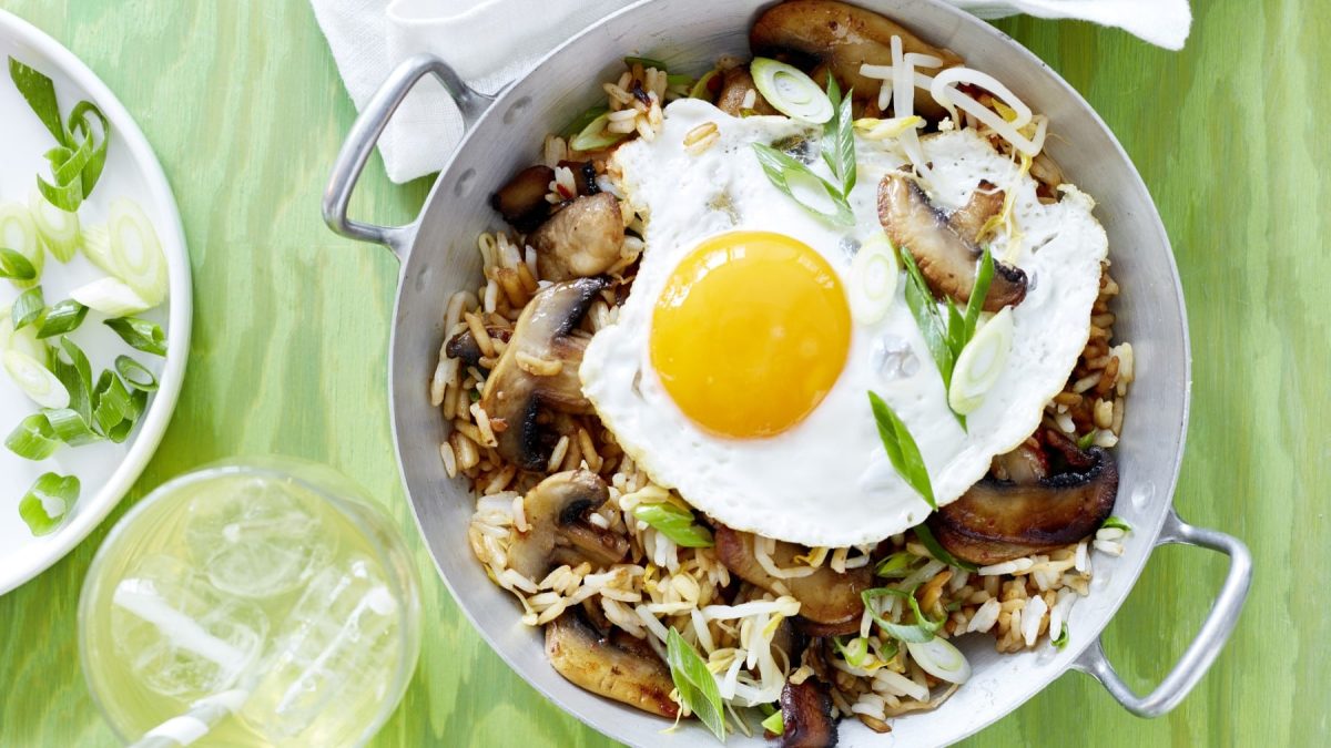 Grüner Untergrund mit silberner Pfanne und dem Essen von oben fotografiert.