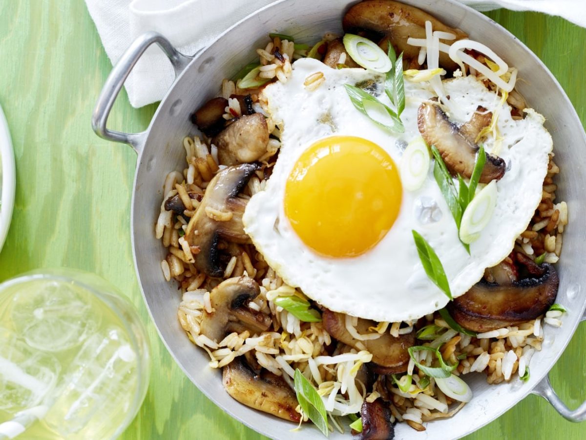 Grüner Untergrund mit silberner Pfanne und dem Essen von oben fotografiert.