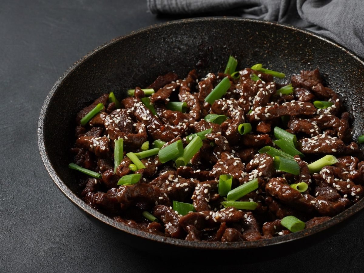 Eine schwarze Pfanne mit dem Rindfleisch in dunkler Sauce.