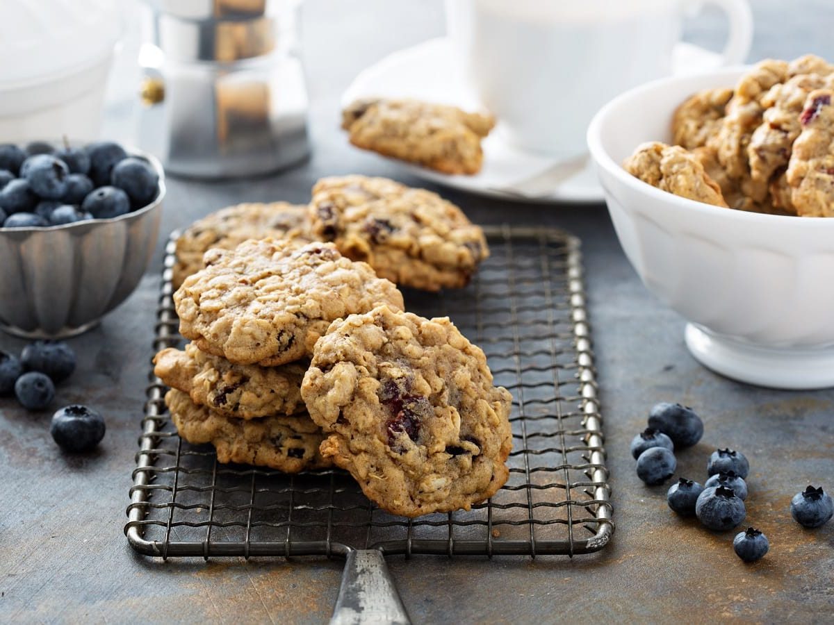 Ein Stapel mit Blaubeer-Hafer-Cookies auf einem schwarzen Gitter.