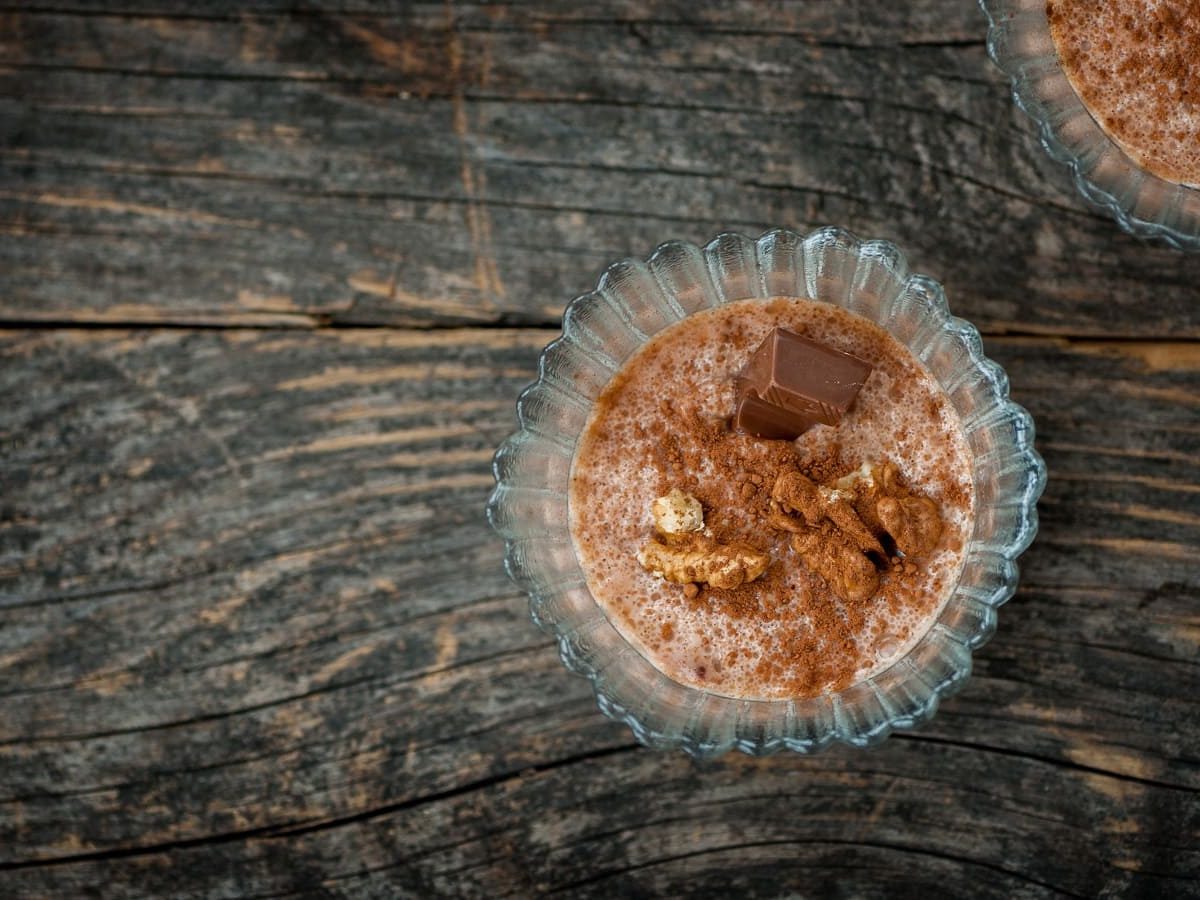 Ein Dessertglas mit einer Portion Biscoff-Pudding auf einem Holztisch.