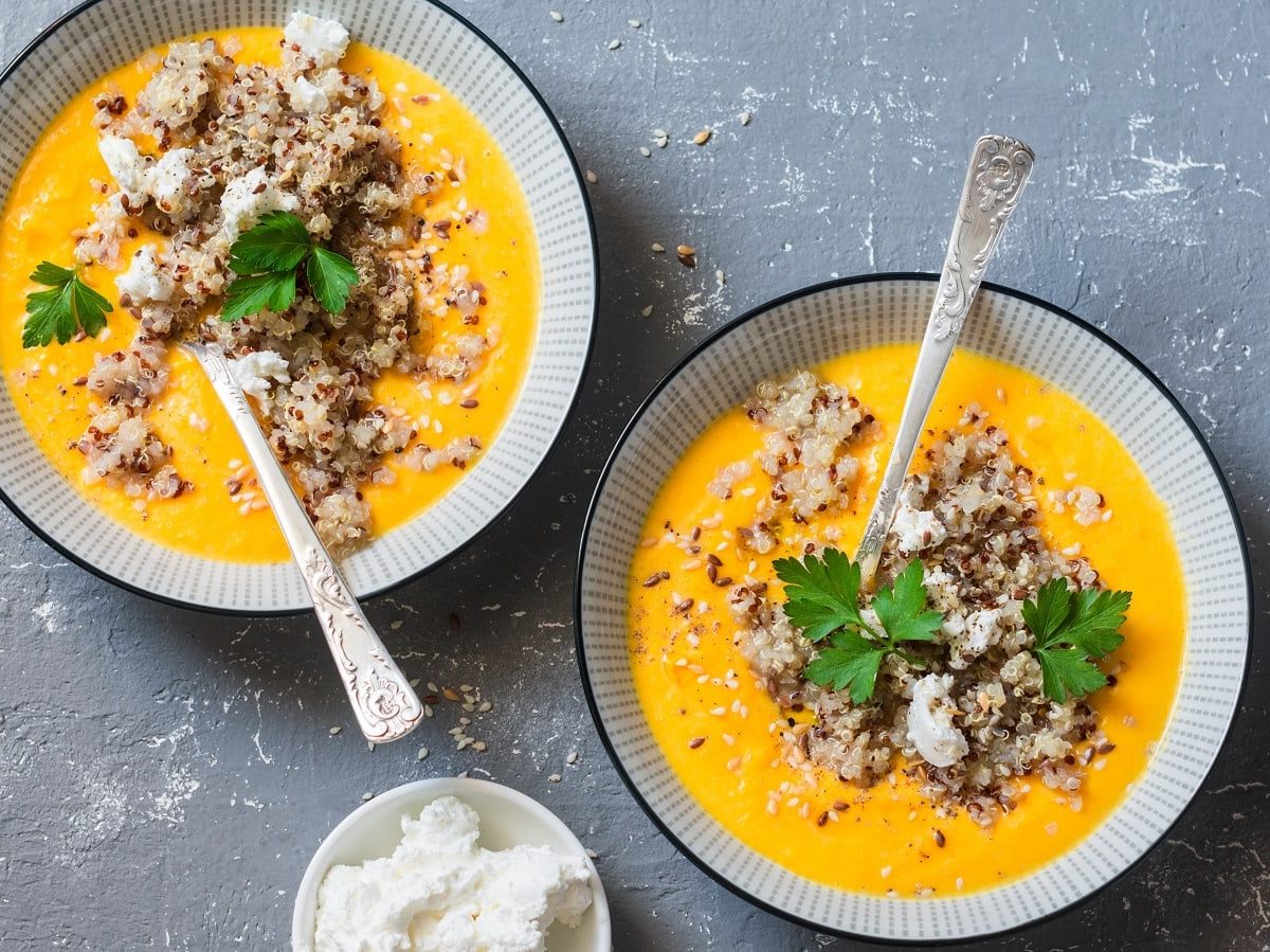 Zwei Schüsseln mit Quinoa-Kürbissuppe auf einem grauen Untergrund.