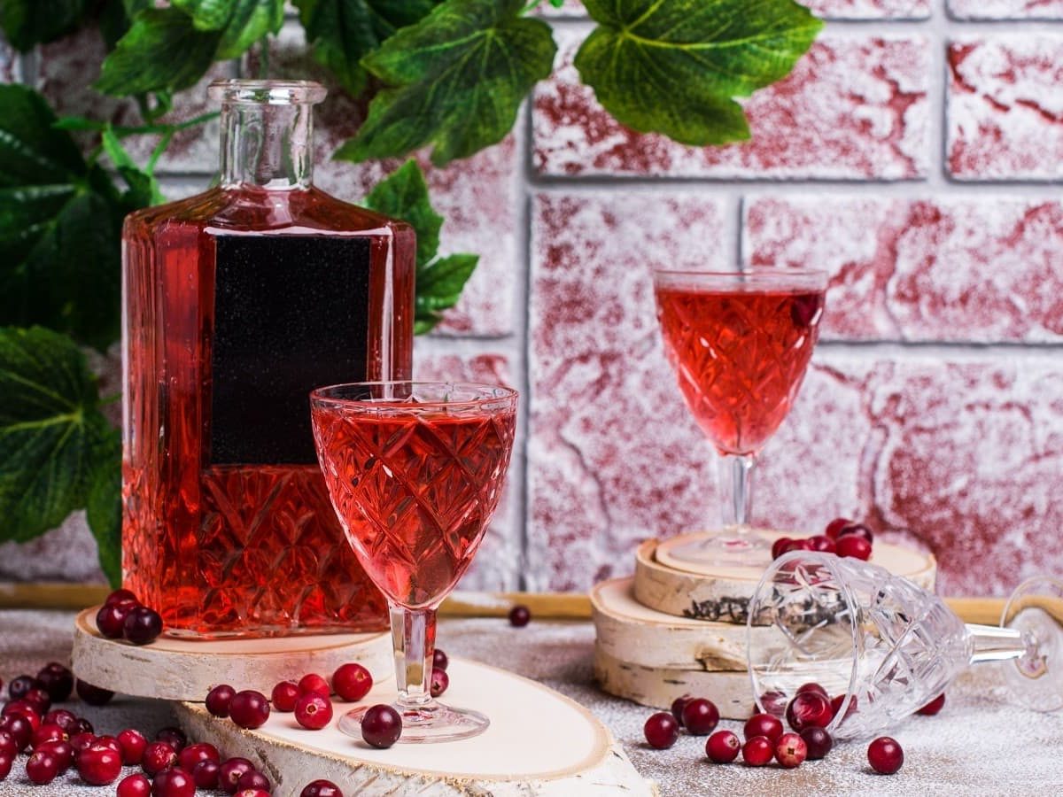 Zwei Gläser und eine Flasche aus Glas mit Cranberry-Likör.