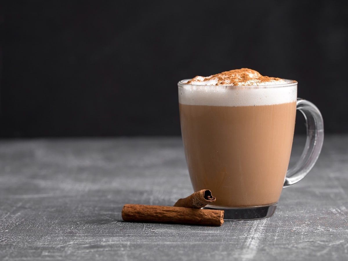 Eine Tasse Zimtstern-Latte vor einem schwarzen Hintergrund.