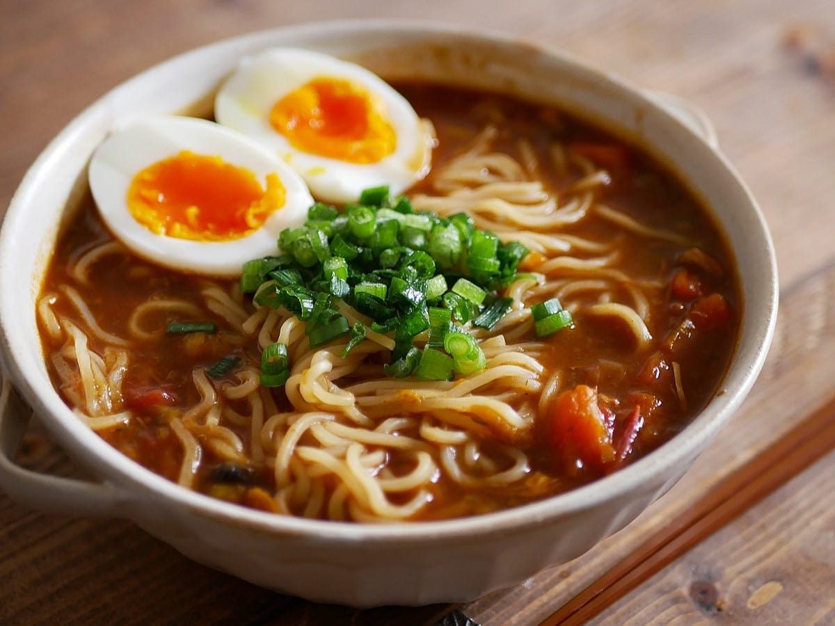 Eine Schüssel Curry Ramen auf einem braunen Holztisch.