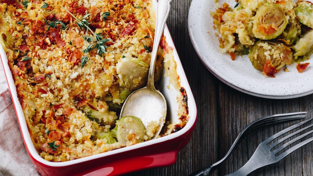 Draufsicht: Eine teilweise Ansicht eines Brüsseler Gratins mit Rosenkohl. Daneben ist ein Teller mit Brüsseler Gratin mit Rosenkohl.