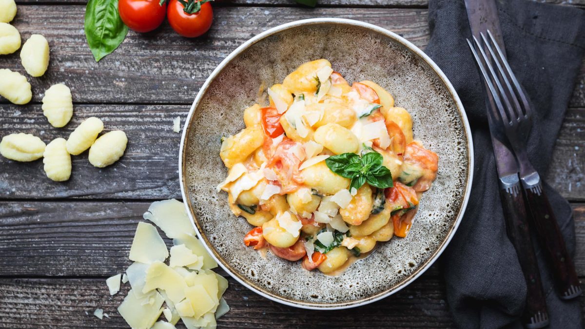 Frisch zubereitete Gnocchi in einer cremigen Tomaten-Sahne-Sauce mit Basilikum, serviert auf einem tiefen, rustikalen Teller.