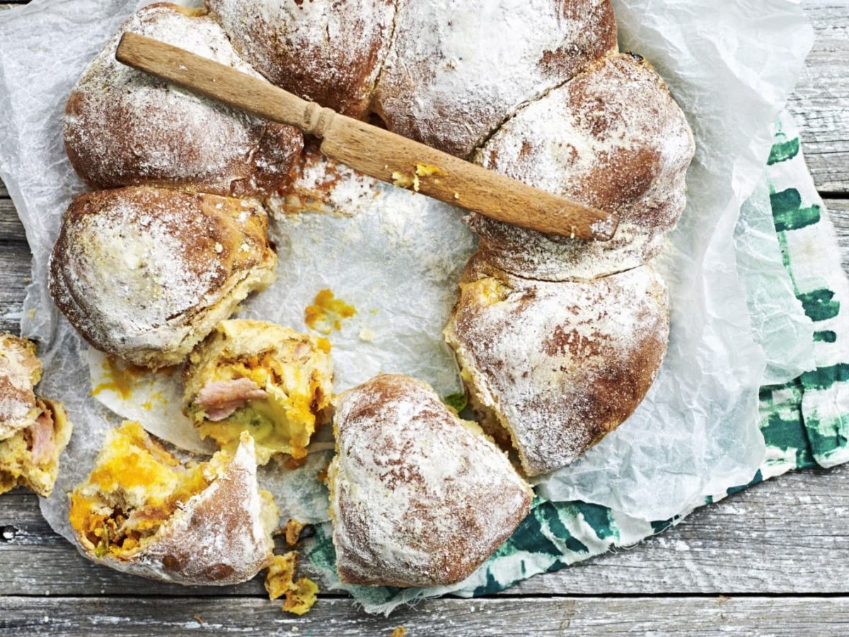 Gefüllte Zupfbrötchen mit Kürbis auf einem Holztisch.