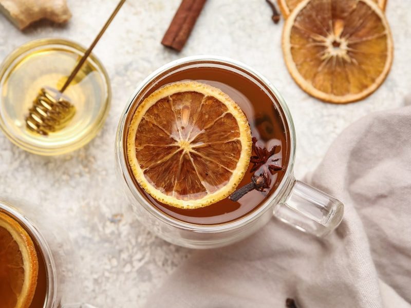 Eine Tasse Orangen-Zimt-Tee auf einem weißen Tuch.