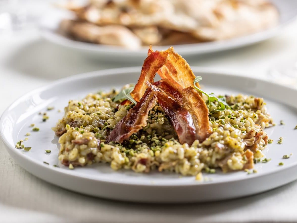 Ein grauer Teller mit Pistazien-Risotto darauf.