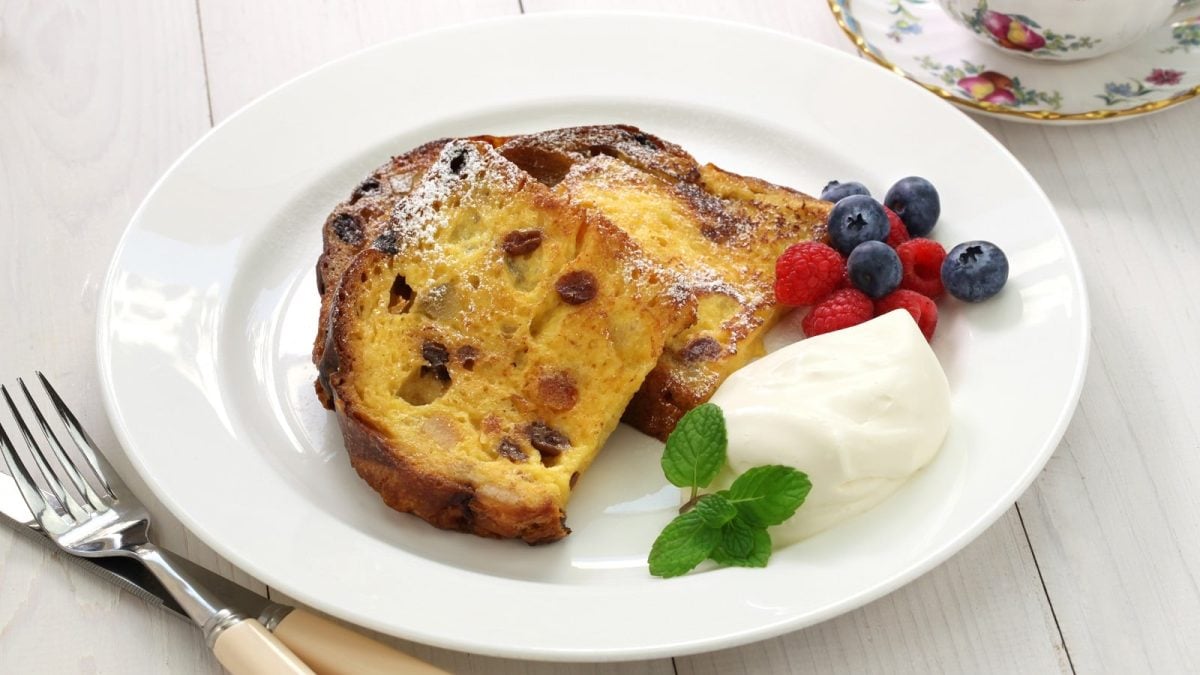 Ein weißer Teller mit Panettone French Toast auf einem weißen Tisch.