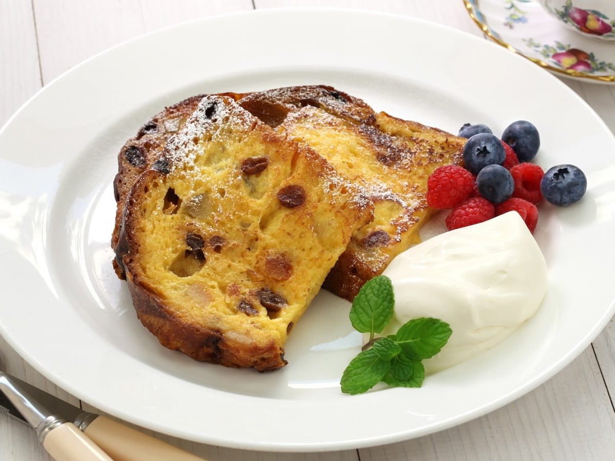 Ein weißer Teller mit Panettone French Toast auf einem weißen Tisch.