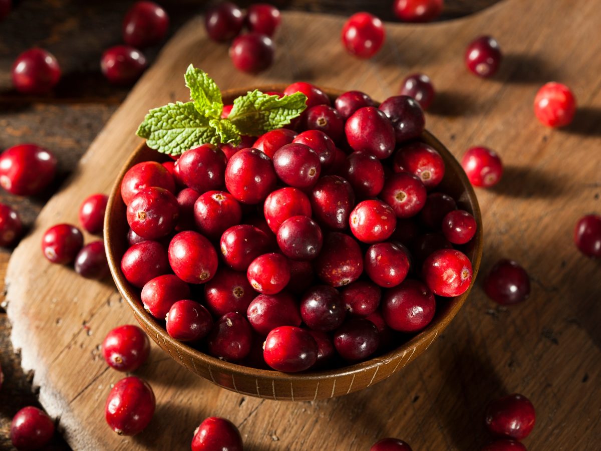 Frische Cranberries in einer Holzschüssel auf einem Tisch.