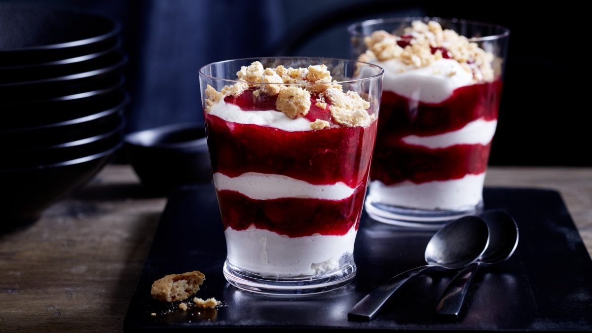 Zwei Gläser mit Grannys gelöffelter Cheesecake auf einem schwarzen Tablett.