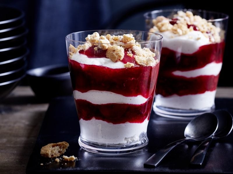 Zwei Gläser mit Grannys gelöffelter Cheesecake auf einem schwarzen Tablett.