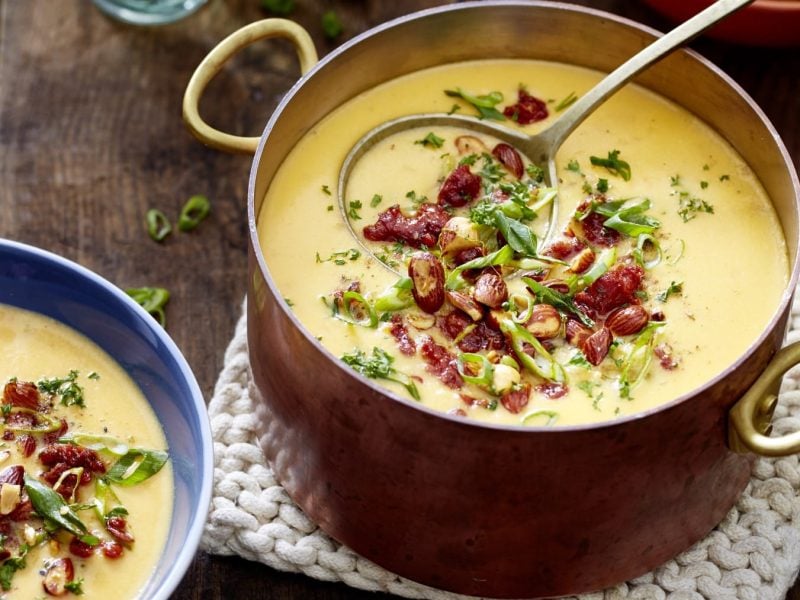 Zwei Portionen Fondue-Eintopf mit Chorizo auf einem braunen Holztisch.