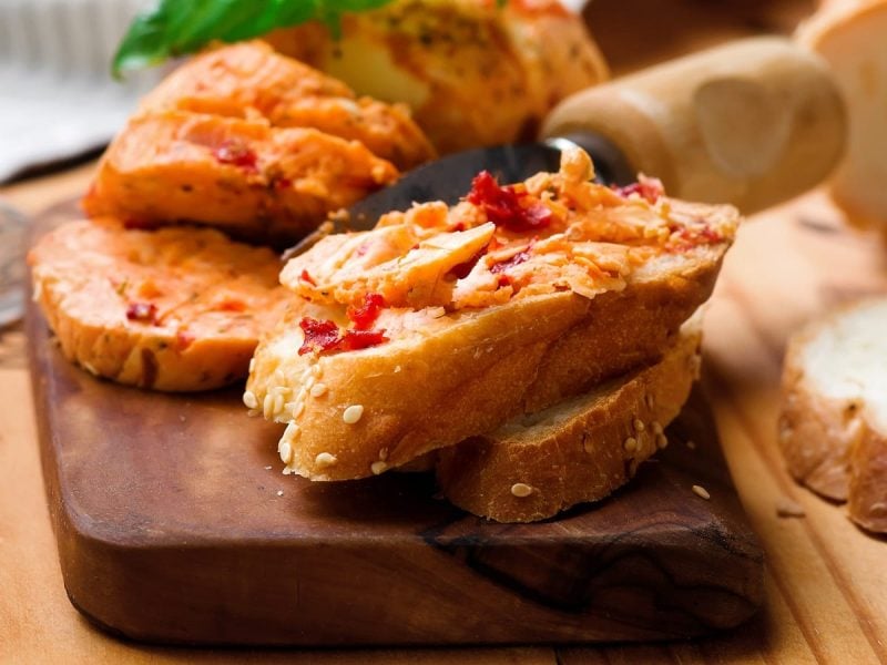 Ein Holzbrett mit Pizzabutter auf Brotscheiben.