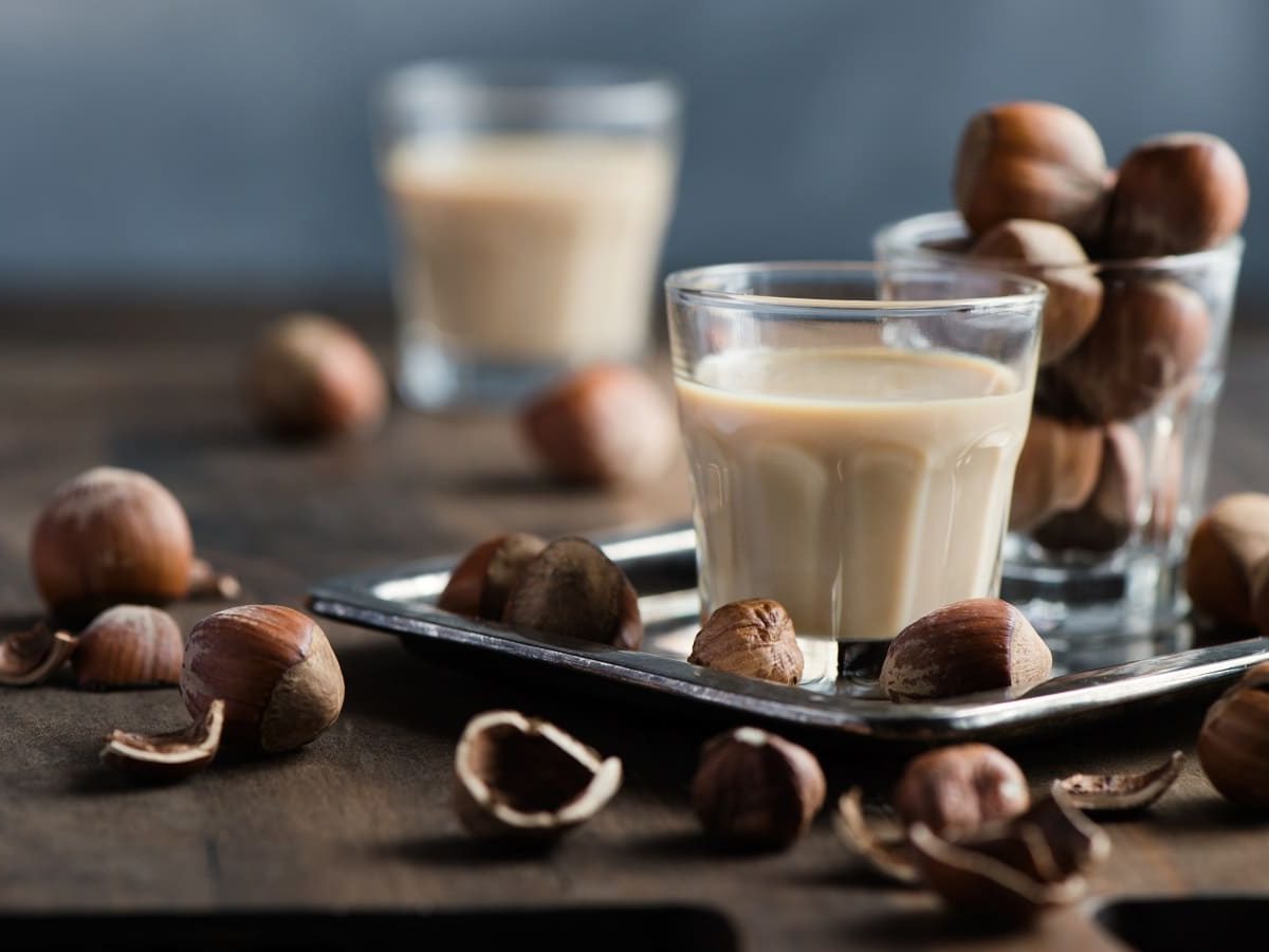 Zwei Shot-Gläser mit Giotto-Likör auf einem braunen Holztisch.