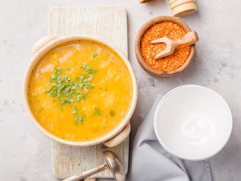 Eine Schüssel Kardamom-Linsensuppe auf einem hellgrauen Untergrund.