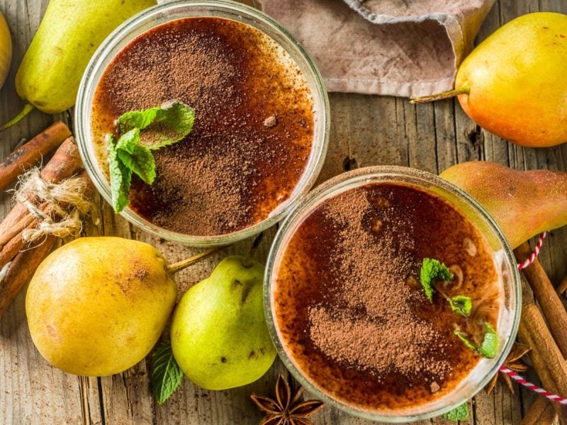 Zwei Gläser Chai-Birnen-Smoothie auf einem Holztisch.