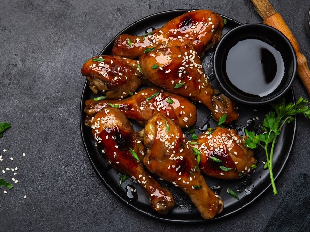 Ein schwarzer Teller mit Soy Sauce Chicken auf einem grauen Tisch.