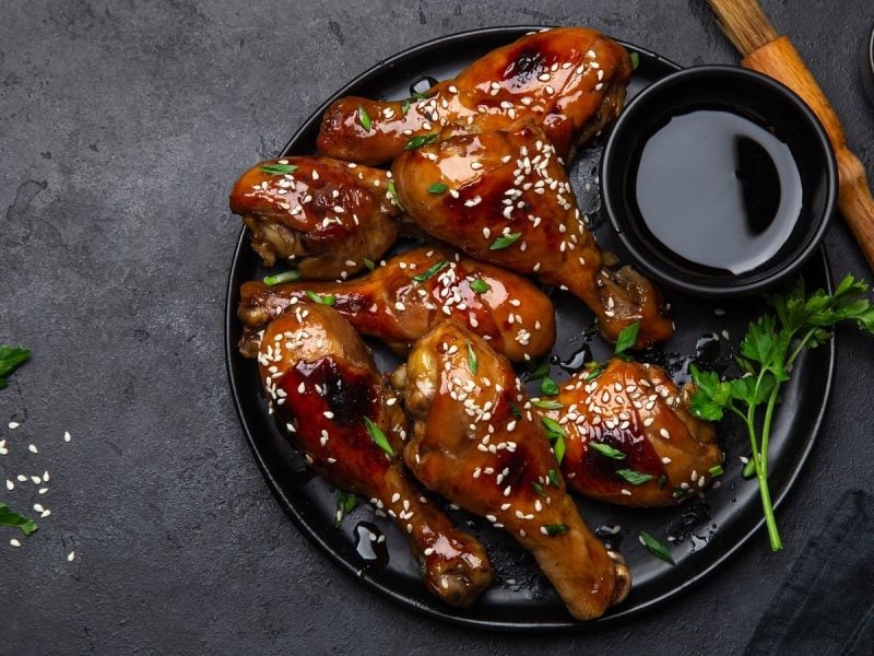 Ein schwarzer Teller mit Soy Sauce Chicken auf einem grauen Tisch.