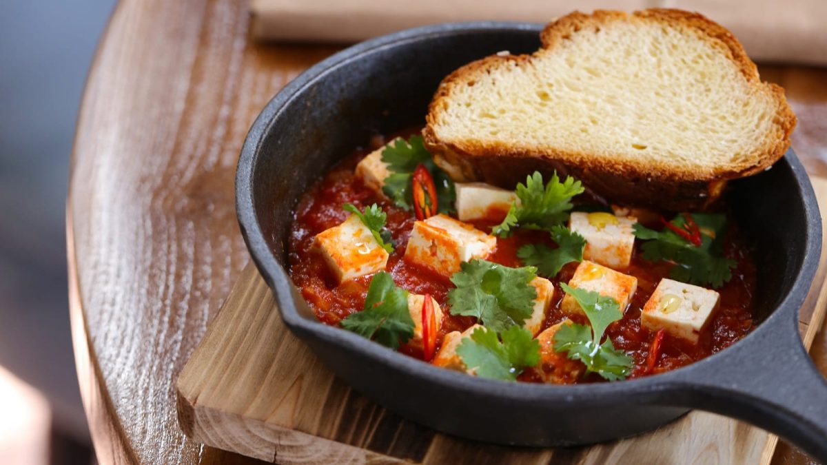 Eine schwarze gusseiserne Pfanne mit Tofu Shakshuka.