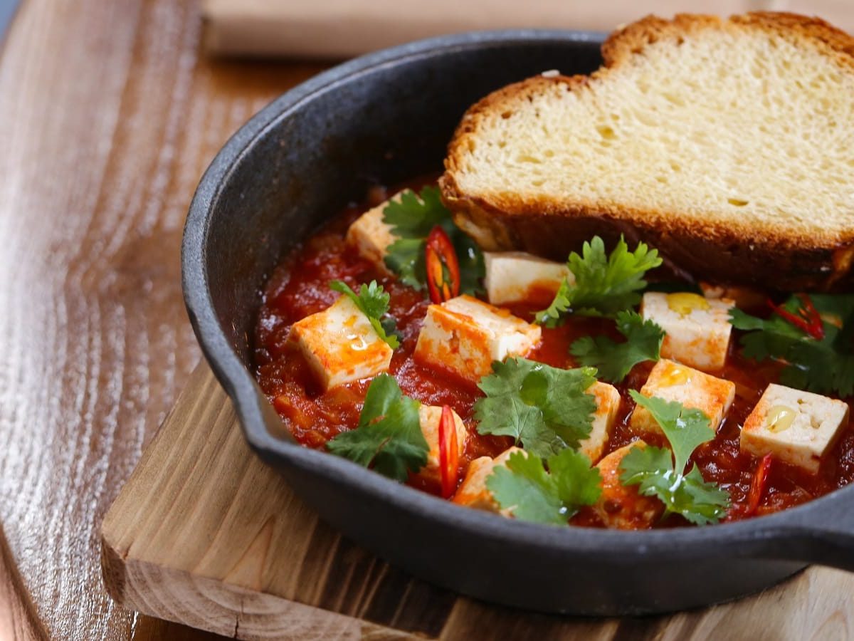 Eine schwarze gusseiserne Pfanne mit Tofu Shakshuka.