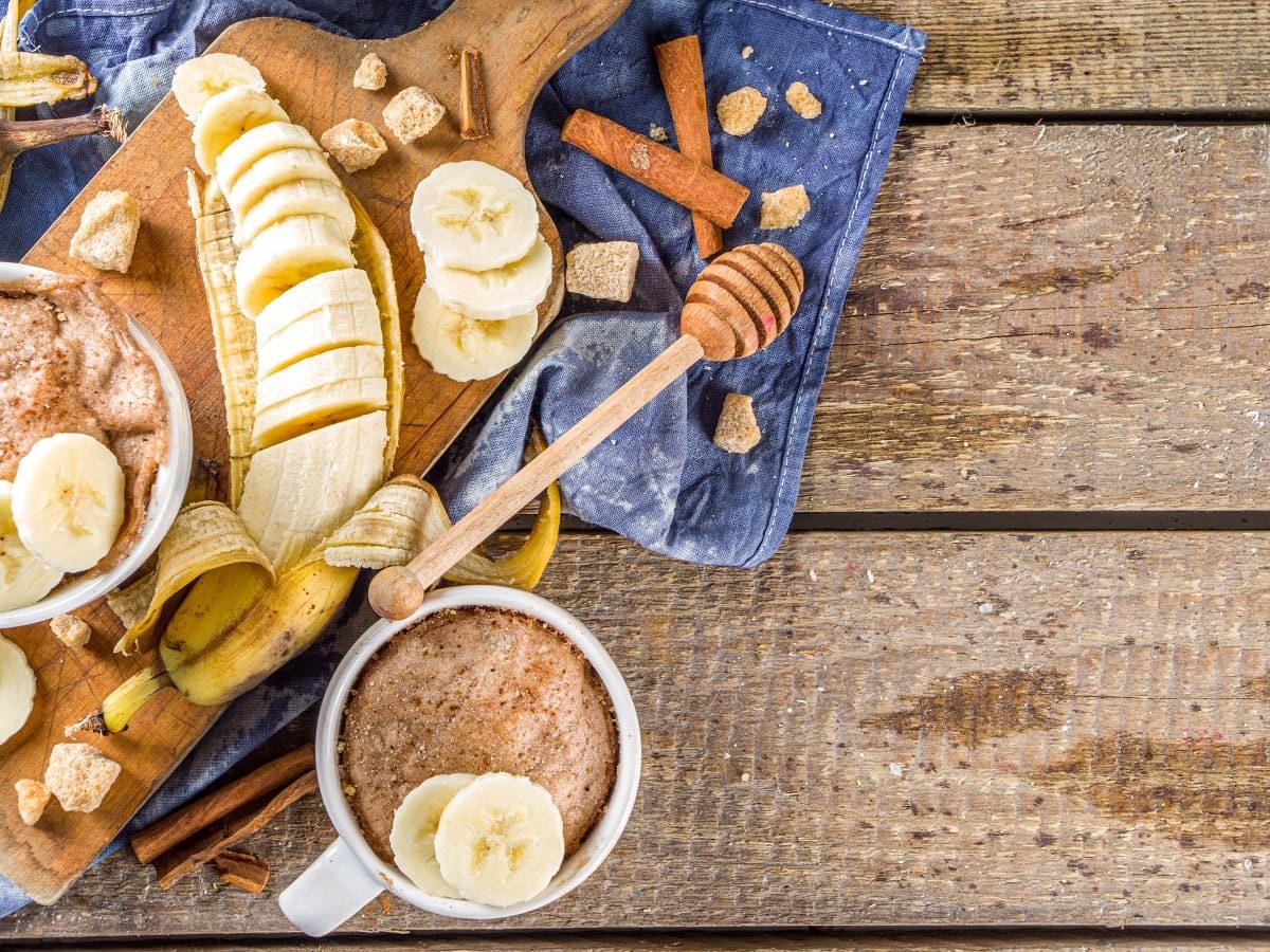 Zwei Bananenbrot Mug Cakes auf einem Holztisch.