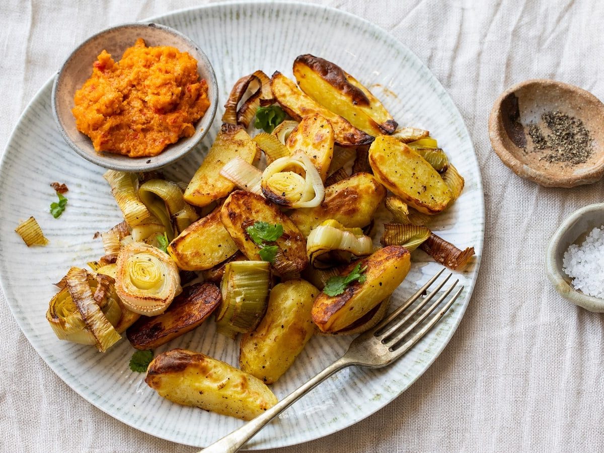 Ein Teller mit einer Portion Curry-Kartoffel-Pfanne auf einem hellen Holztisch.