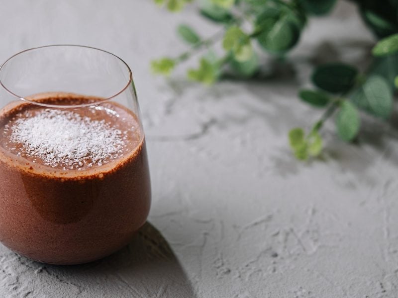 Ein Glas Choco Coco Smoothie auf einem grauen Tisch.