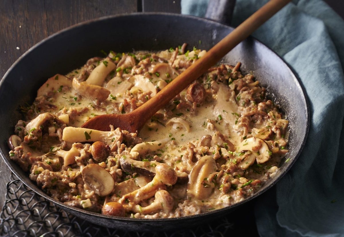 Pfanne mit gebratenem Hackfleisch und gemischten Pilzen in einer cremigen Sauce.