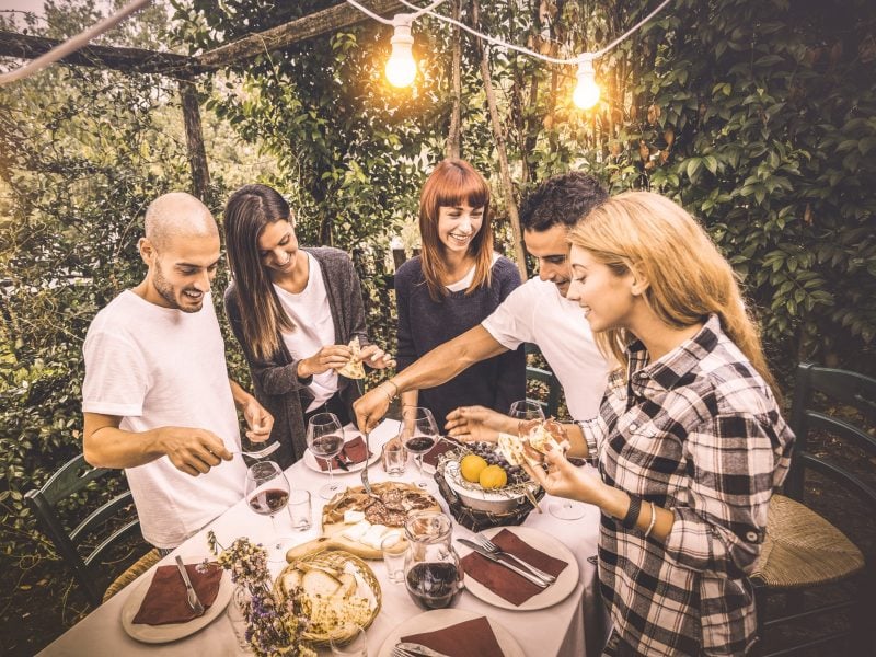 Fünf Freunde, die um einen Tisch stehen und ein italienisches Menü genießen.