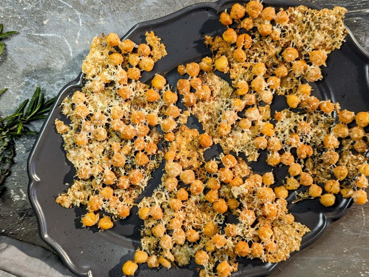 Die Chips auf einem dunklen Teller und grauem Untergrund von oben fotografiert. Daneben frische Kräuter und ein Stück Parmesan.