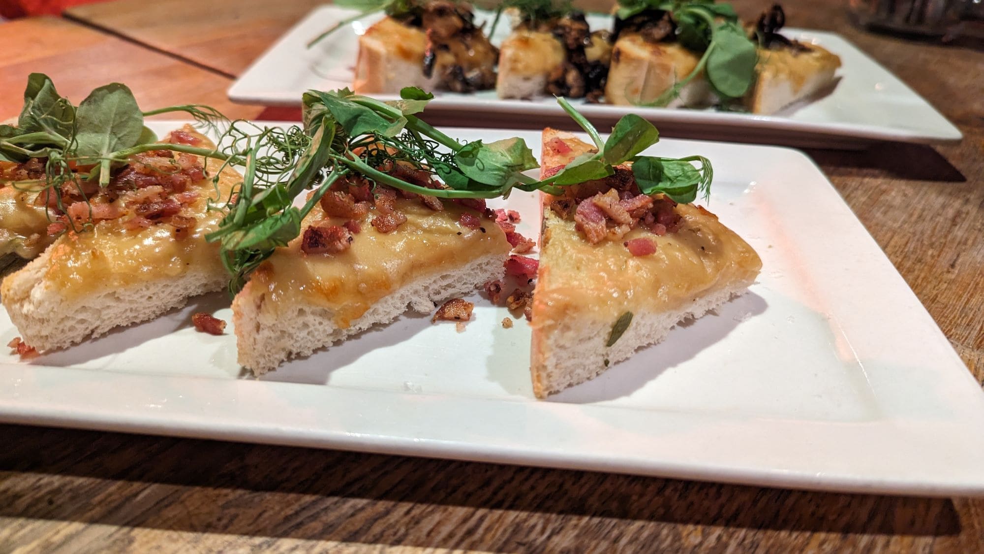 Mehrere Scheiben Welsh Rarebit auf weißen Tellern.