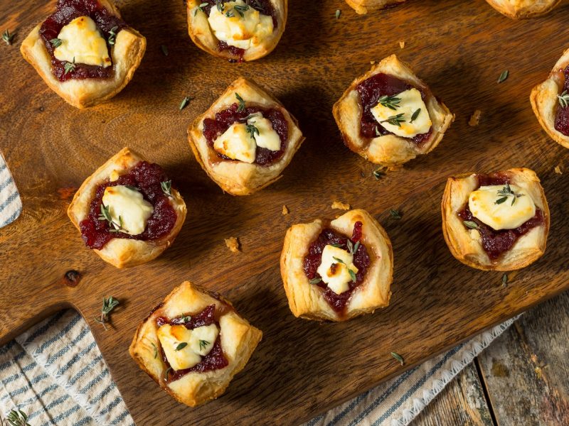 Eine Portion Cranberry-Ziegenkäse-Bites auf einem Holzbrett.