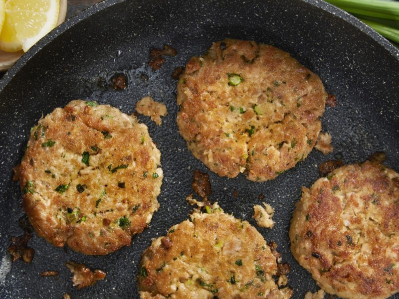 Vier Thunfisch-Küchlein in der Pfanne direkt von oben fotografiert.