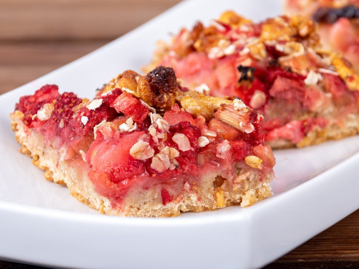 Haferiegel mit Erdbeeren und Rhabarber in Nahaufnahme auf einem weißen Tablett.