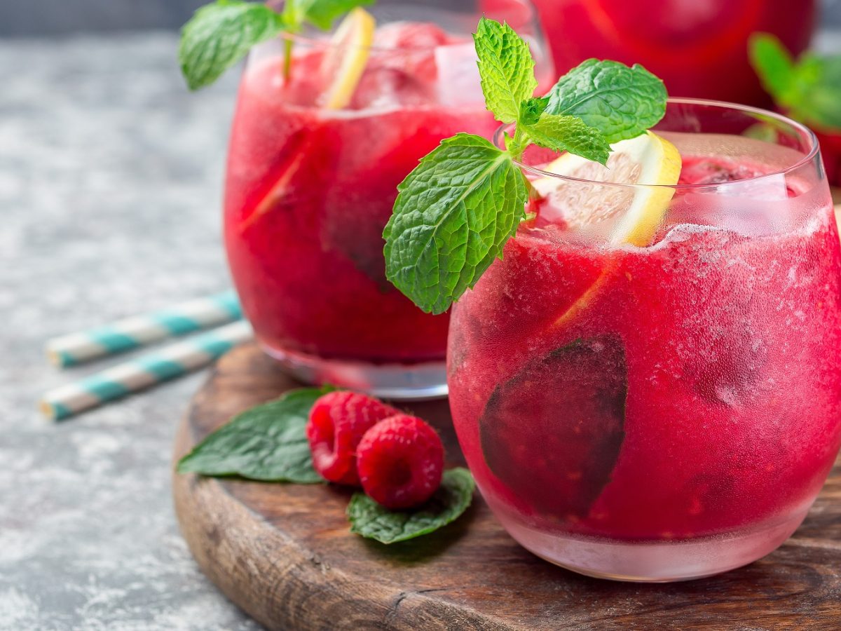 Himbeerlimonade in zwei Gläser, garniert mit frischer Minze und Zitronenscheiben.