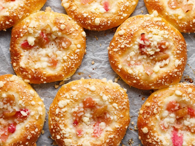 Rhabarberbrötchen mit Streuseln auf Backpapier.