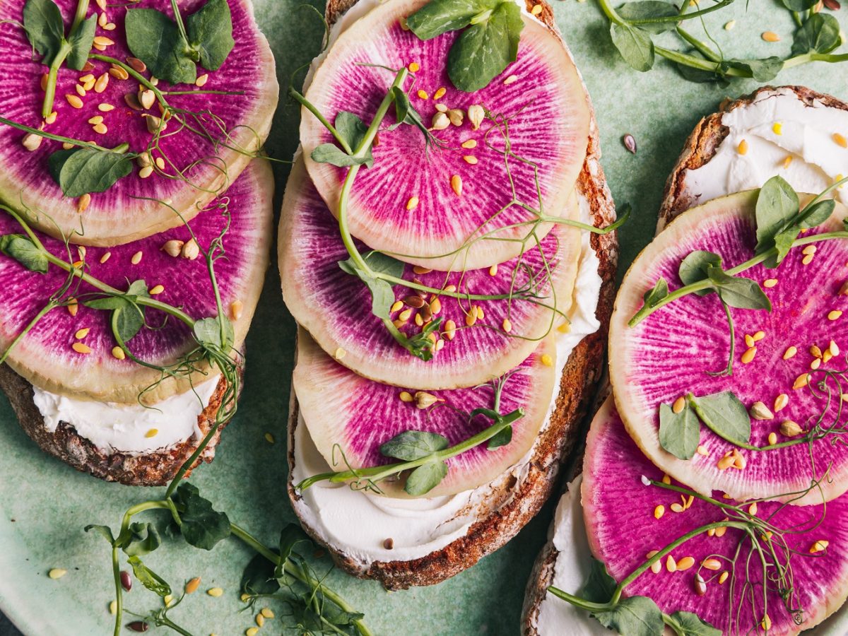 Stulle mit Wassermelonen-Rettich, Frischkäse und Micro-Greens auf einem grünen Teller.