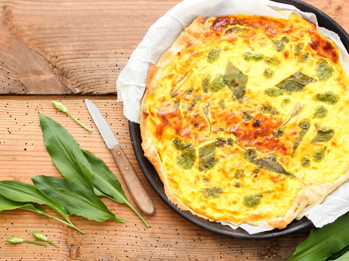 Draufsicht auf Wildkräuter-Quiche und frischen Bärlauch.