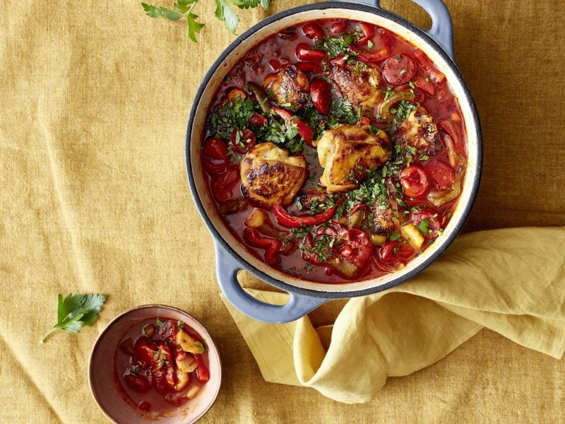 Andalusicher Chorizo-Hähnchen-Pott in einem Suppentopf. Daneben Schüssel mit dem Eintopf.