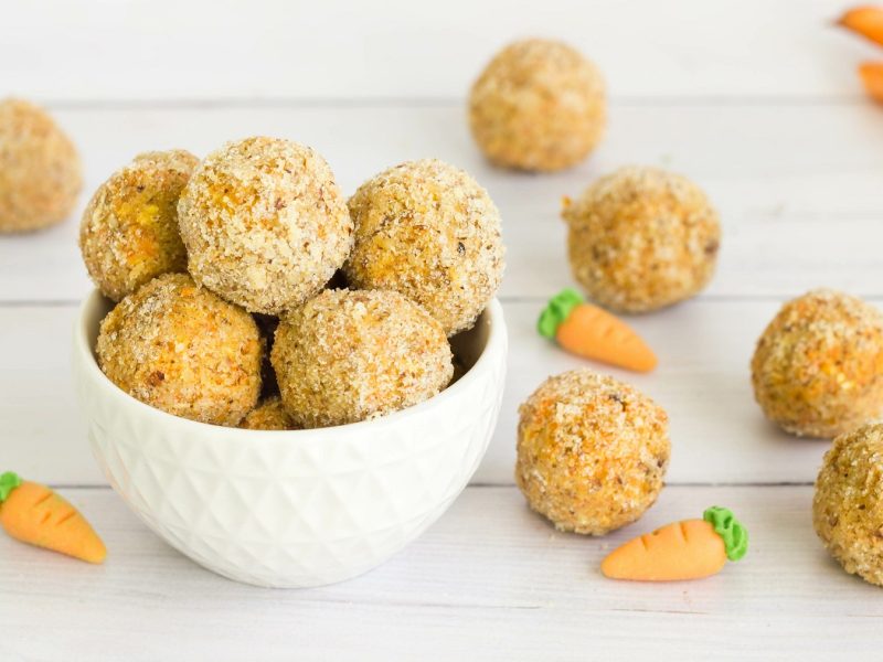 Carrot-Cake Energy-Balls gestapelt und neben einer weißen Schüssel.