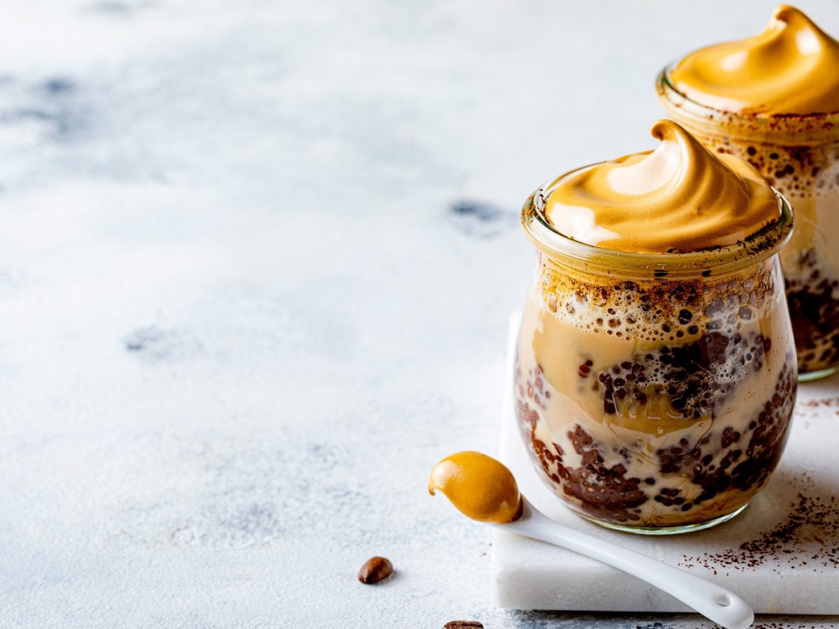 Dalgona Chia-Pudding in zwei kleinen Weck-Gläsern vor einem hellen Hintergrund.